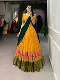 Woman in a yellow and green traditional outfit with floral patterns taking a mirror selfie.