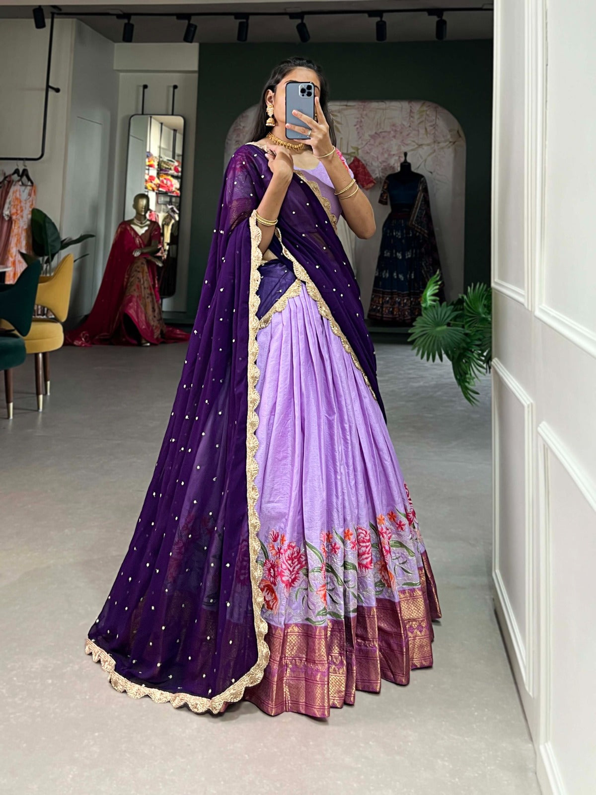 Person wearing a purple and lavender saree with floral patterns in a room.